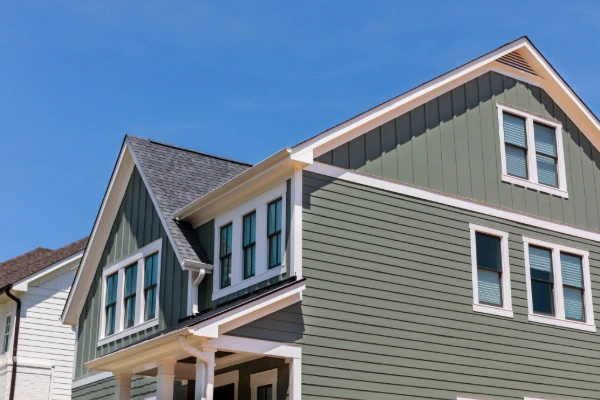 Two-story home featuring green horizontal and vertical siding with contrasting white trim.