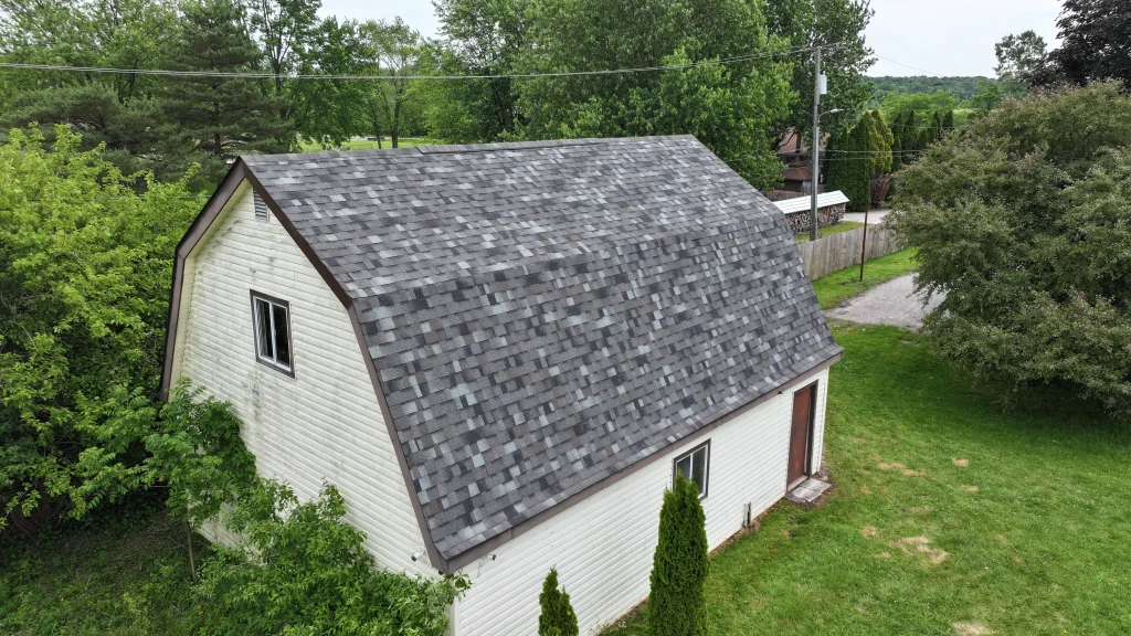 Completed gray asphalt shingle roof replacement on a detached garage